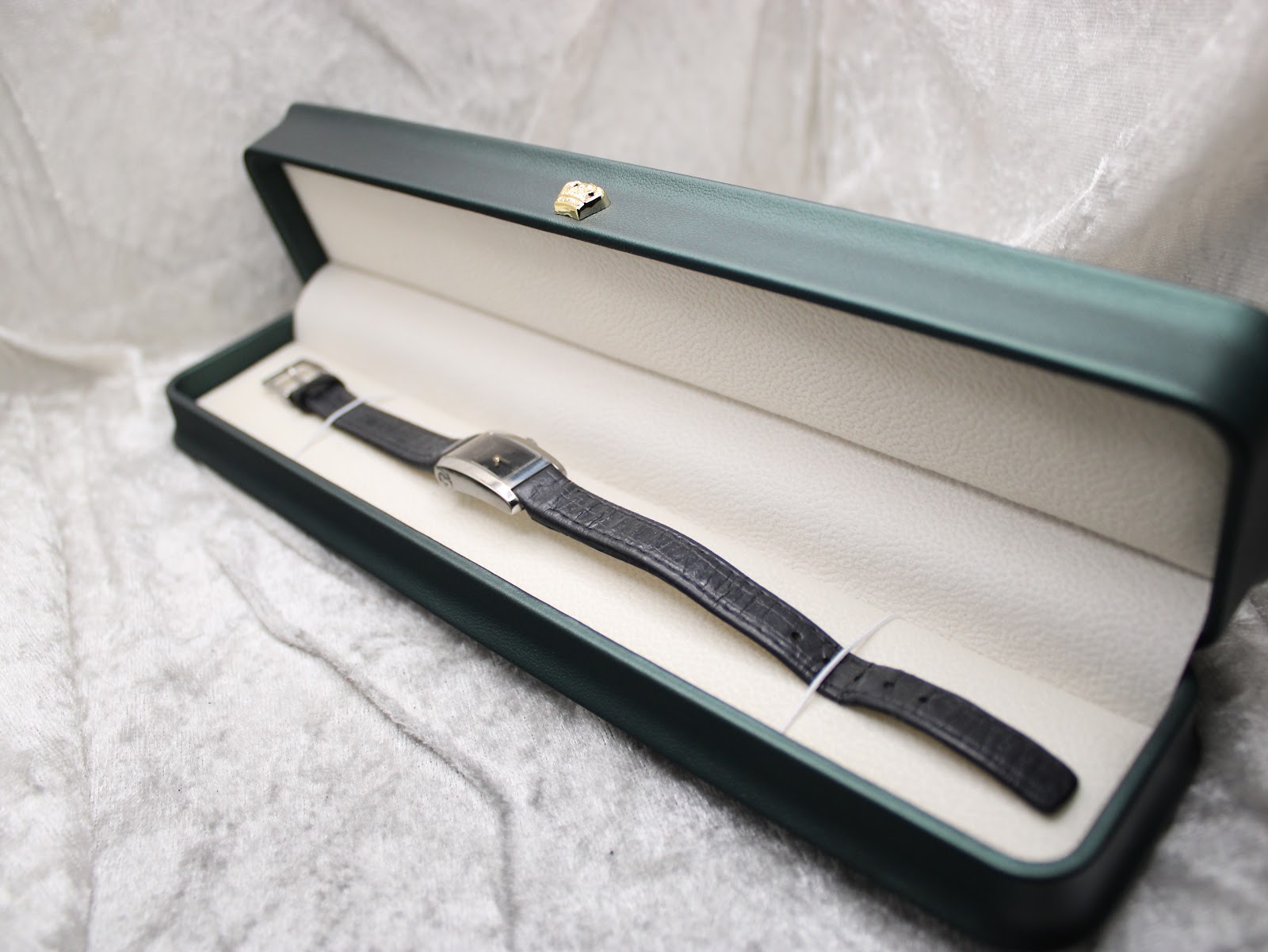 The Gucci 8600L watch resting neatly inside a dark green presentation box with a cream-coloured interior.