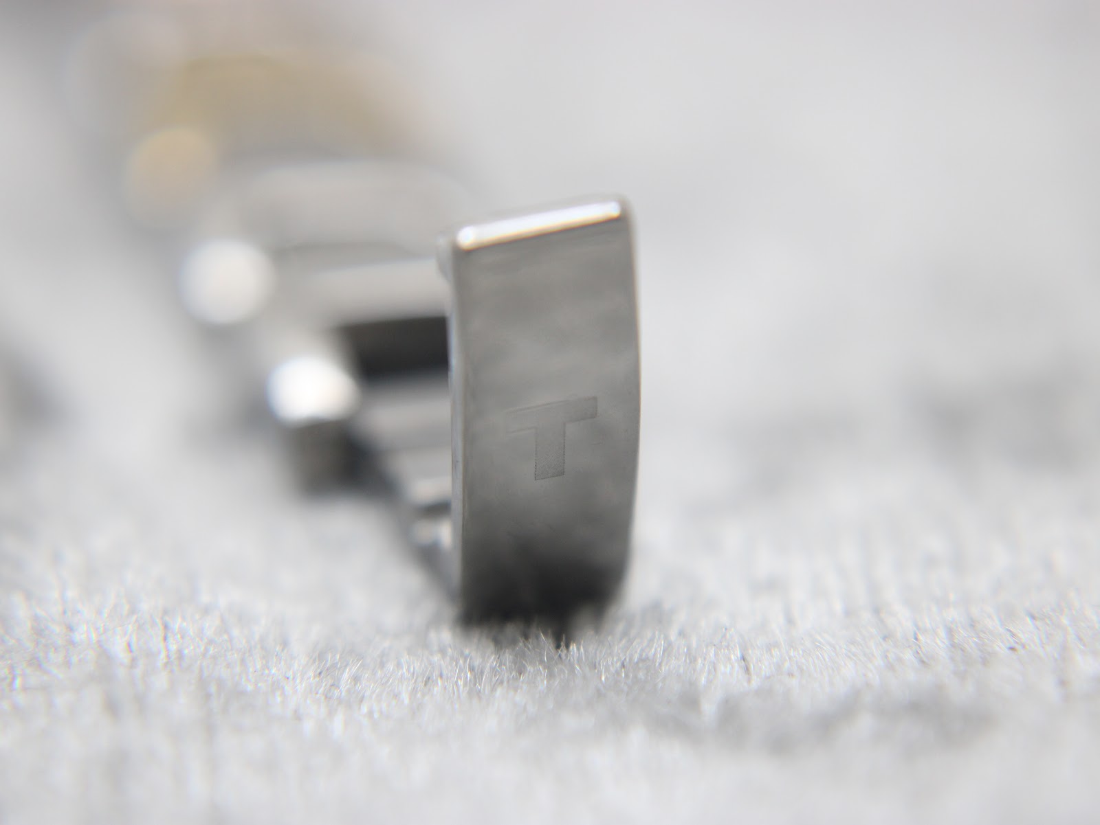 Close-up of the clasp on the Tissot G350 bracelet, showing the embossed 'T' logo.