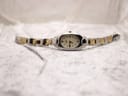 Full view of the Tissot G350 two-tone bracelet and oval watch head laid flat on a textured white surface.