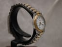 Angled view of the Tissot Seastar D317 on a watch stand, emphasising the gold-tone bezel and the alternating gold and silver links of the bracelet.