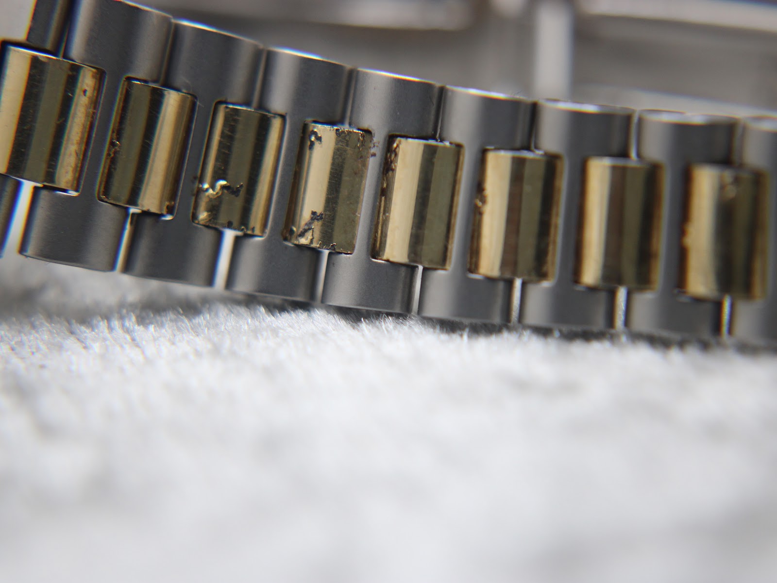 Macro shot of the two-tone bracelet links, revealing some areas of wear and fading on the gold-tone plating.