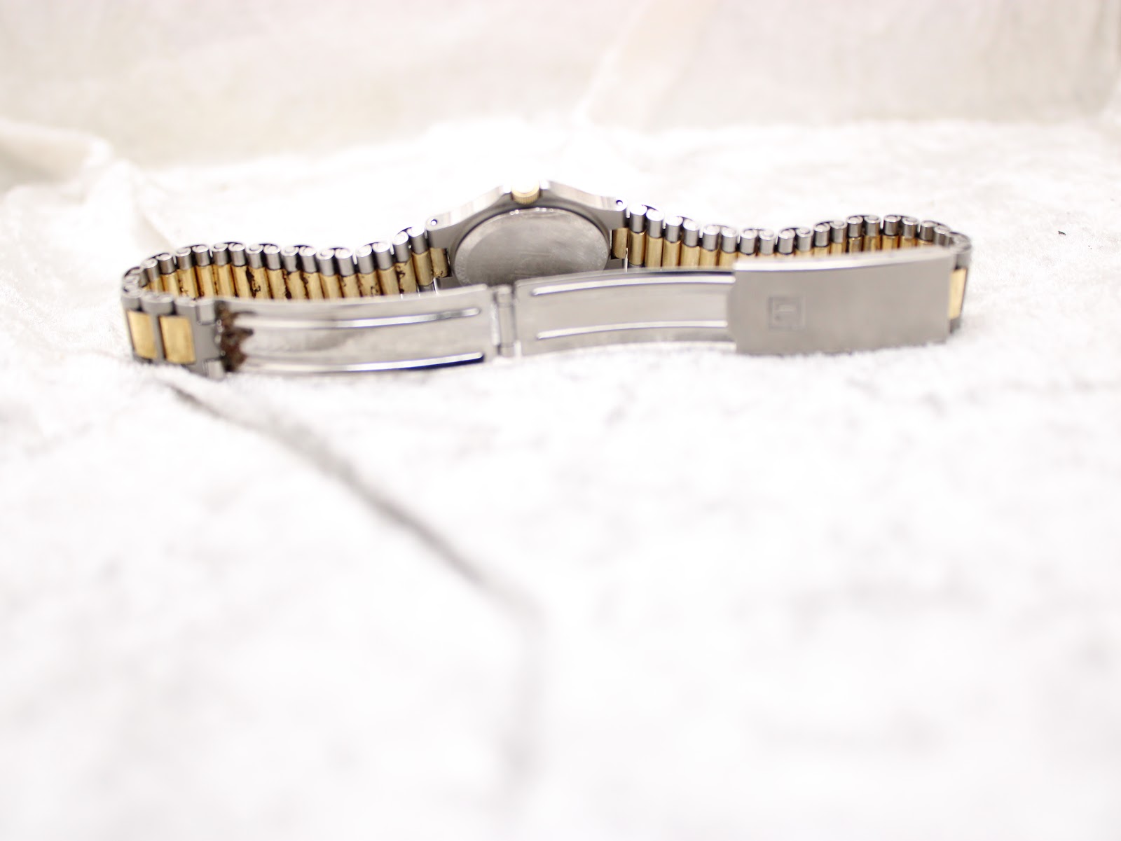 Rear view of the watch with the bracelet open, showing the Tissot signed clasp and the reverse side of the case.