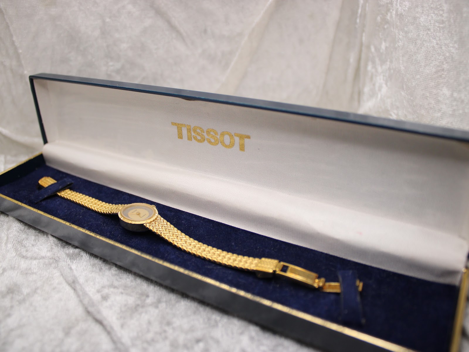 The Tissot ladies' watch with its gold-tone bracelet neatly presented inside its original navy blue Tissot presentation box.