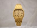 Front view of a vintage Tissot gold tone quartz watch with a textured dial and integrated link bracelet.