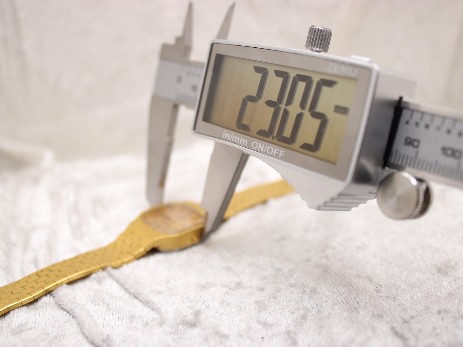 Digital caliper measuring the case width of the Tissot watch, displaying a precise measurement of 23.05mm.