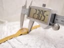 Digital caliper measuring the case width of the Tissot watch, displaying a precise measurement of 23.05mm.