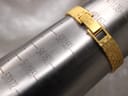 Close-up of the integrated gold tone bracelet and its folding clasp wrapped around a metal ring sizing mandrel, showing a wrist circumference of 175mm.