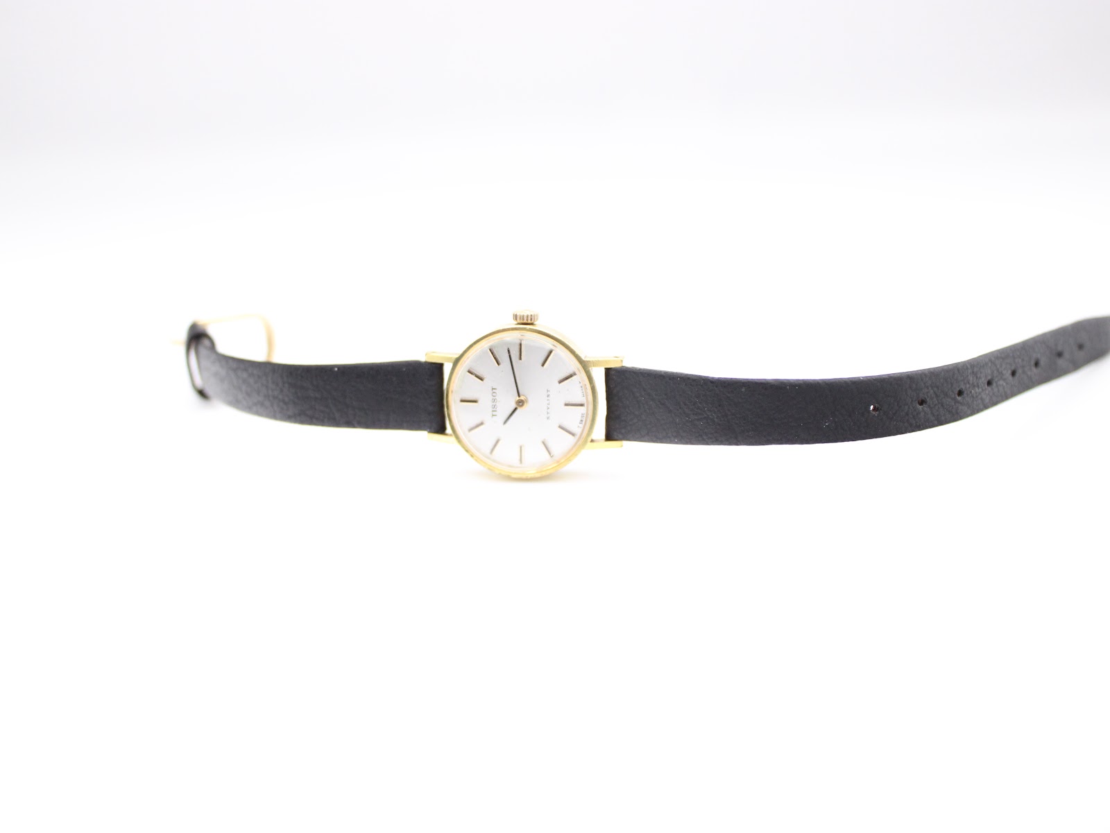 Overhead view of the Tissot Stylist watch with the black leather strap laid flat, showcasing the dial and full length.