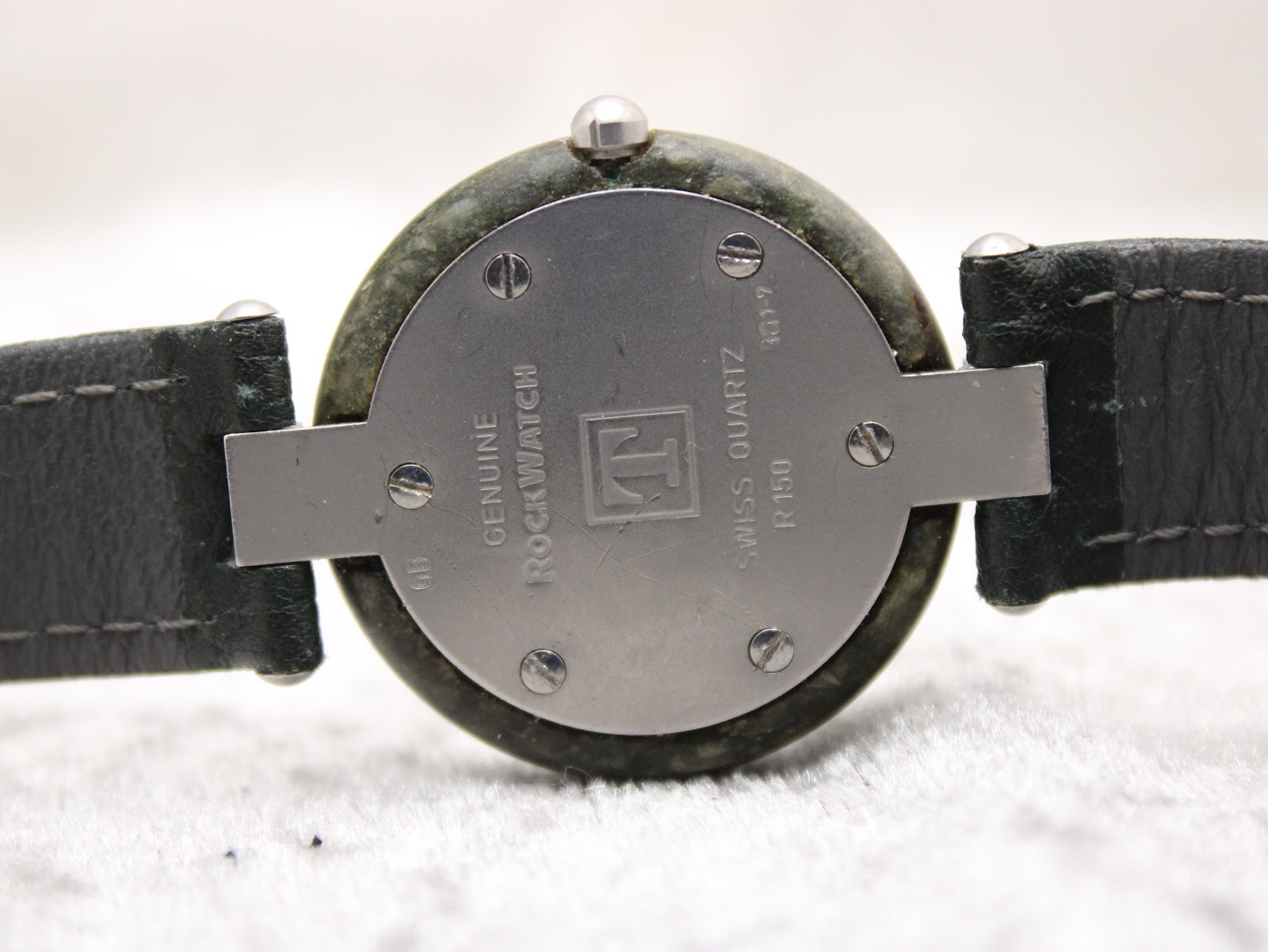Close-up of the stainless steel case back of the Tissot RockWatch, engraved 'GENUINE ROCKWATCH', 'SWISS QUARTZ', and 'R150'.