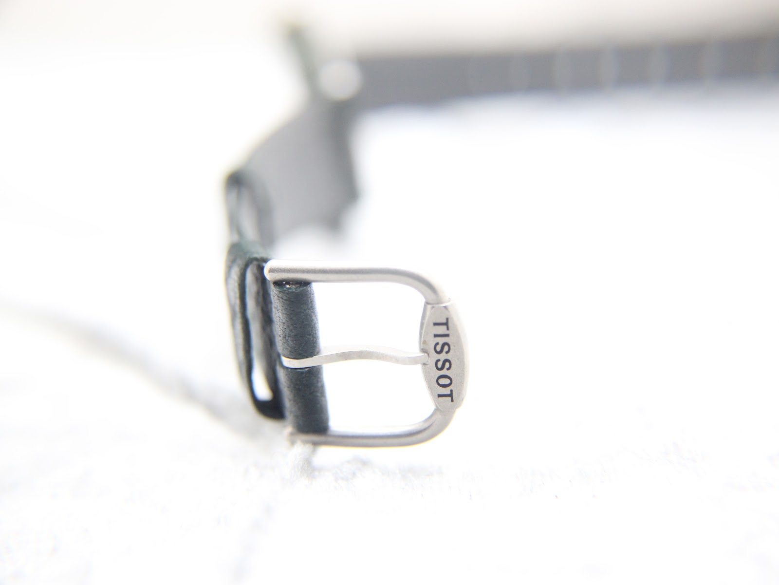 Close-up of the original Tissot signed stainless steel buckle on the green leather strap.