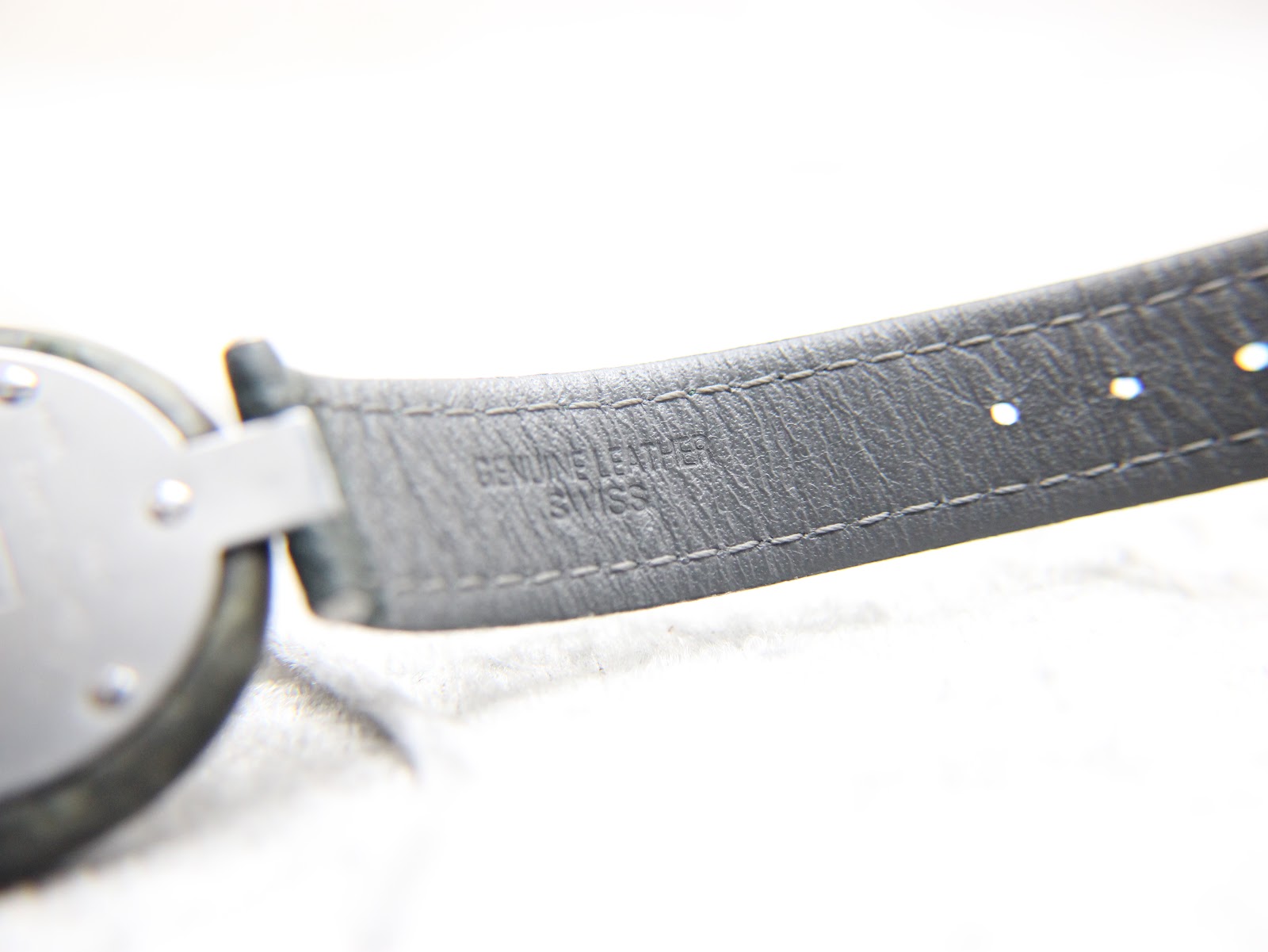 Close-up of the underside of the green leather strap, showing 'GENUINE LEATHER SWISS'.