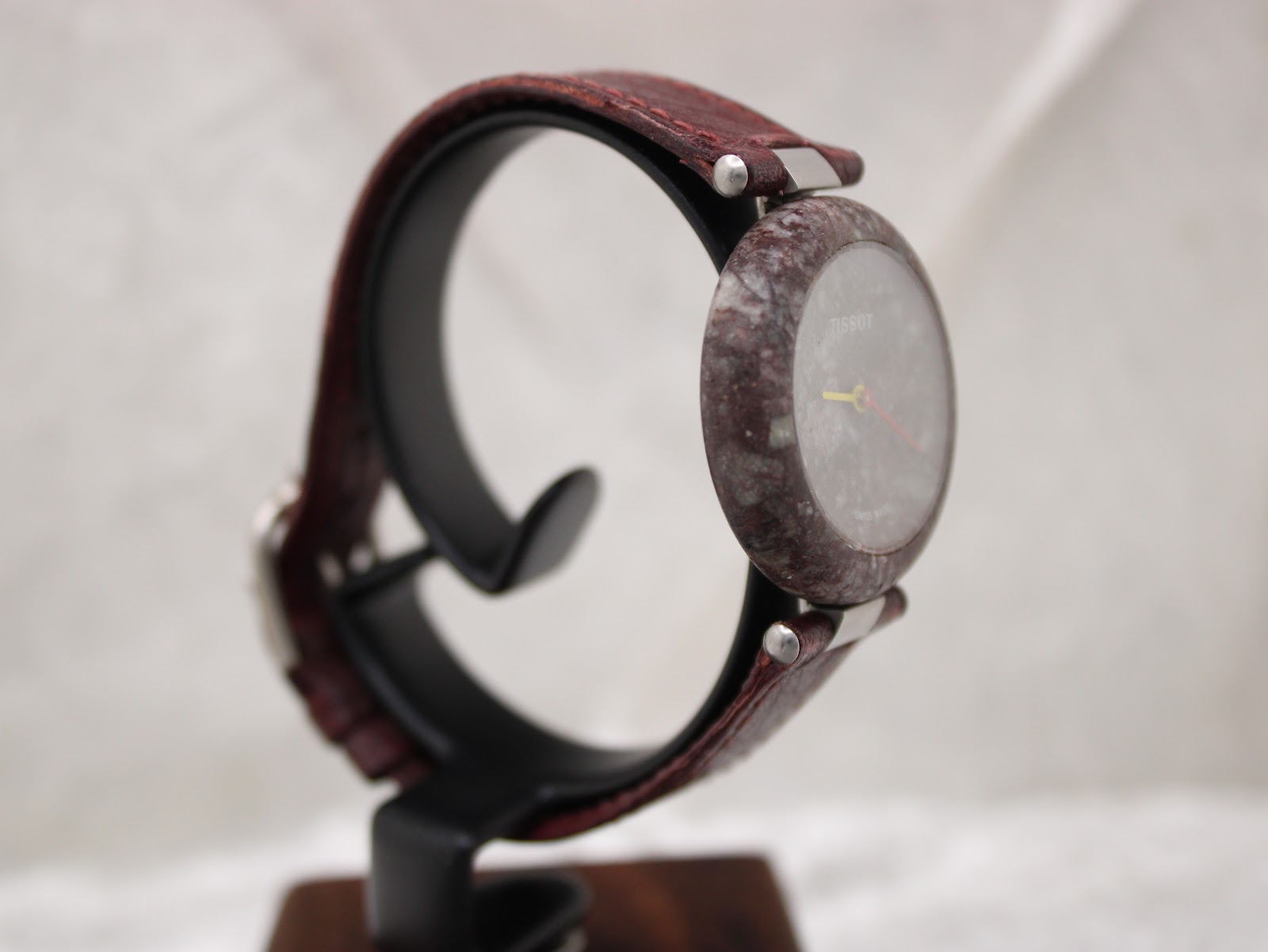 Angled three-quarter view of the Tissot RockWatch on a stand, highlighting the unique pattern of the stone case and dial.