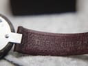 Close-up of the burgundy leather strap, showing its textured finish and embossed 'TISSOT SWISS' text.
