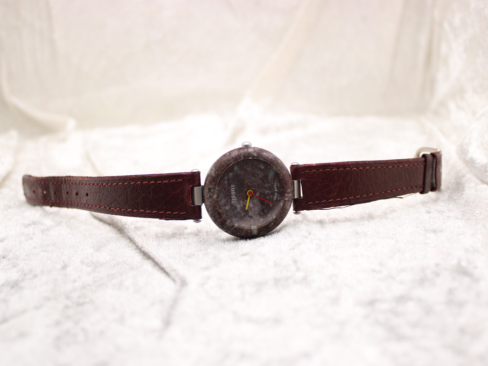 Full view of the Tissot RockWatch lying flat on a white textured surface, displaying the watch and strap fully extended.