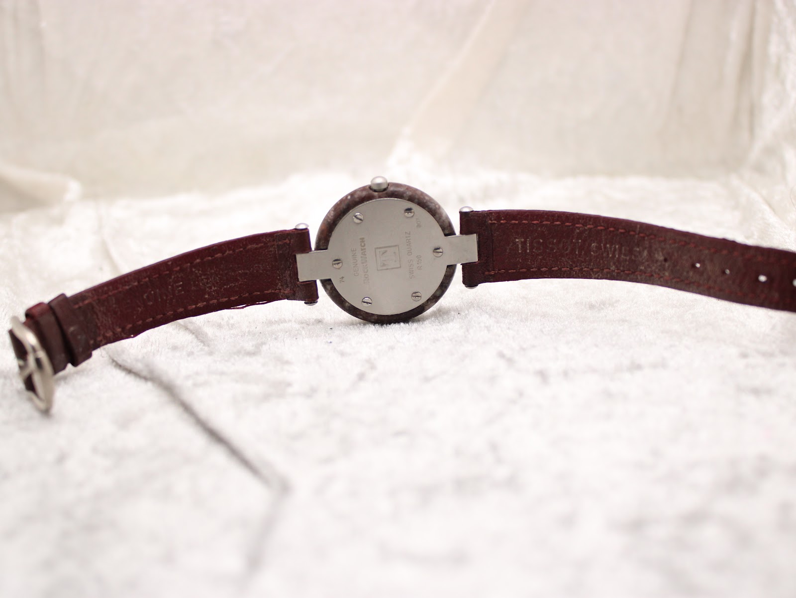 Rear view of the Tissot RockWatch, showing the case back, lug attachment, and extended strap on a white textured surface.