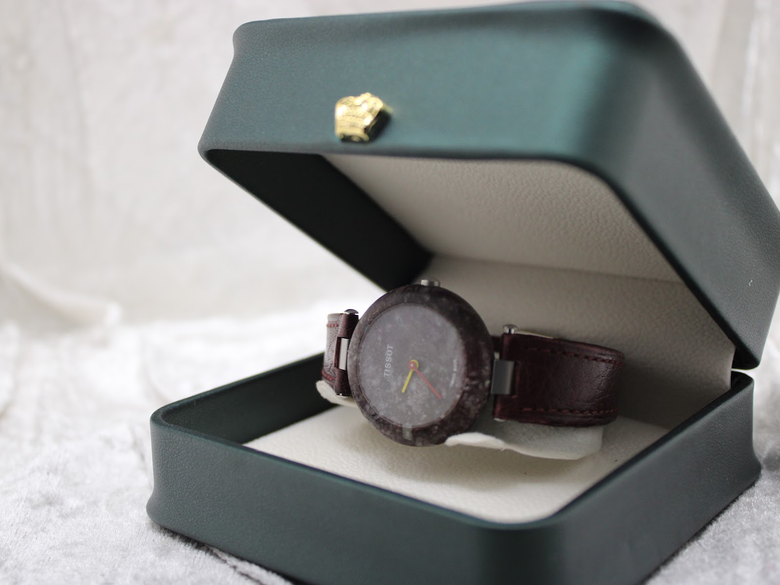 The Tissot RockWatch displayed inside a dark green presentation box on a white textured background.