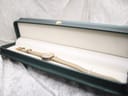 The Gucci 2000L watch with its beige leather strap presented in an open green watch box, on a white textured surface.