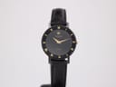Front view of the Raymond Weil Othello 144 watch, showing its black dial with gold Roman numerals and gold hands, on a black leather strap.