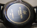 Close-up of the watch case back, engraved with "Raymond Weil Genève" logo, "Water Resistant", and "144", showing some cosmetic wear and a metallic sheen.