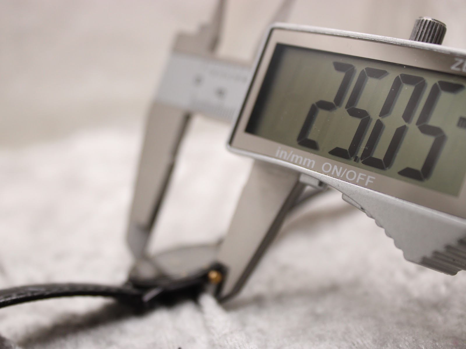 Digital caliper measuring the case diameter of the Raymond Weil Othello watch, displaying a precise measurement of 25.05mm.