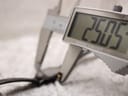 Digital caliper measuring the case diameter of the Raymond Weil Othello watch, displaying a precise measurement of 25.05mm.