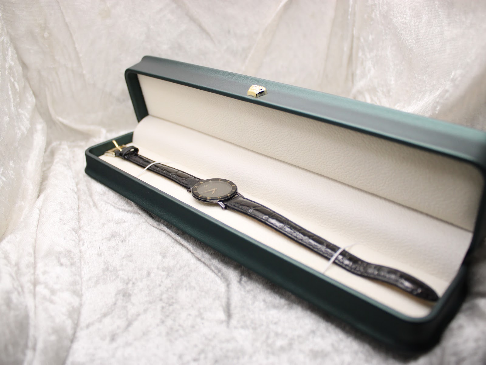 The Raymond Weil Othello watch presented inside a generic rectangular green watch box, on a soft white background.