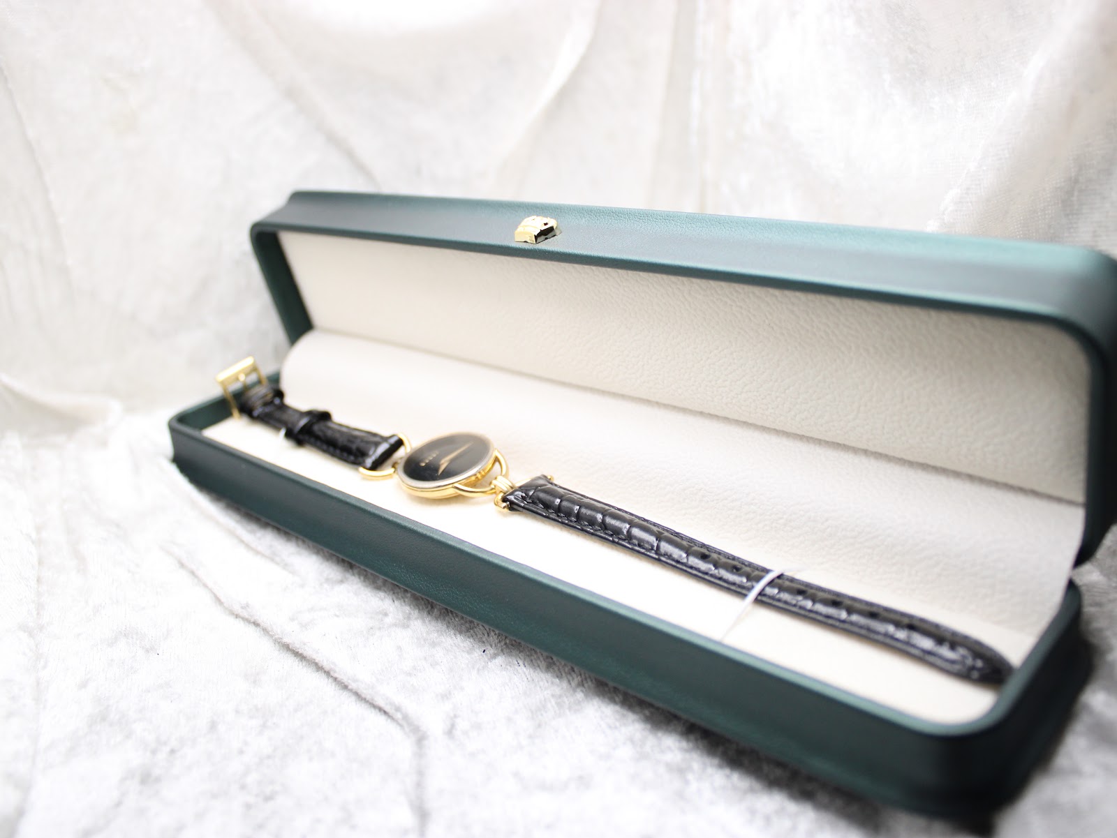 The Gucci 6000.2 L watch presented within a dark green display box, highlighting its elegant presentation.
