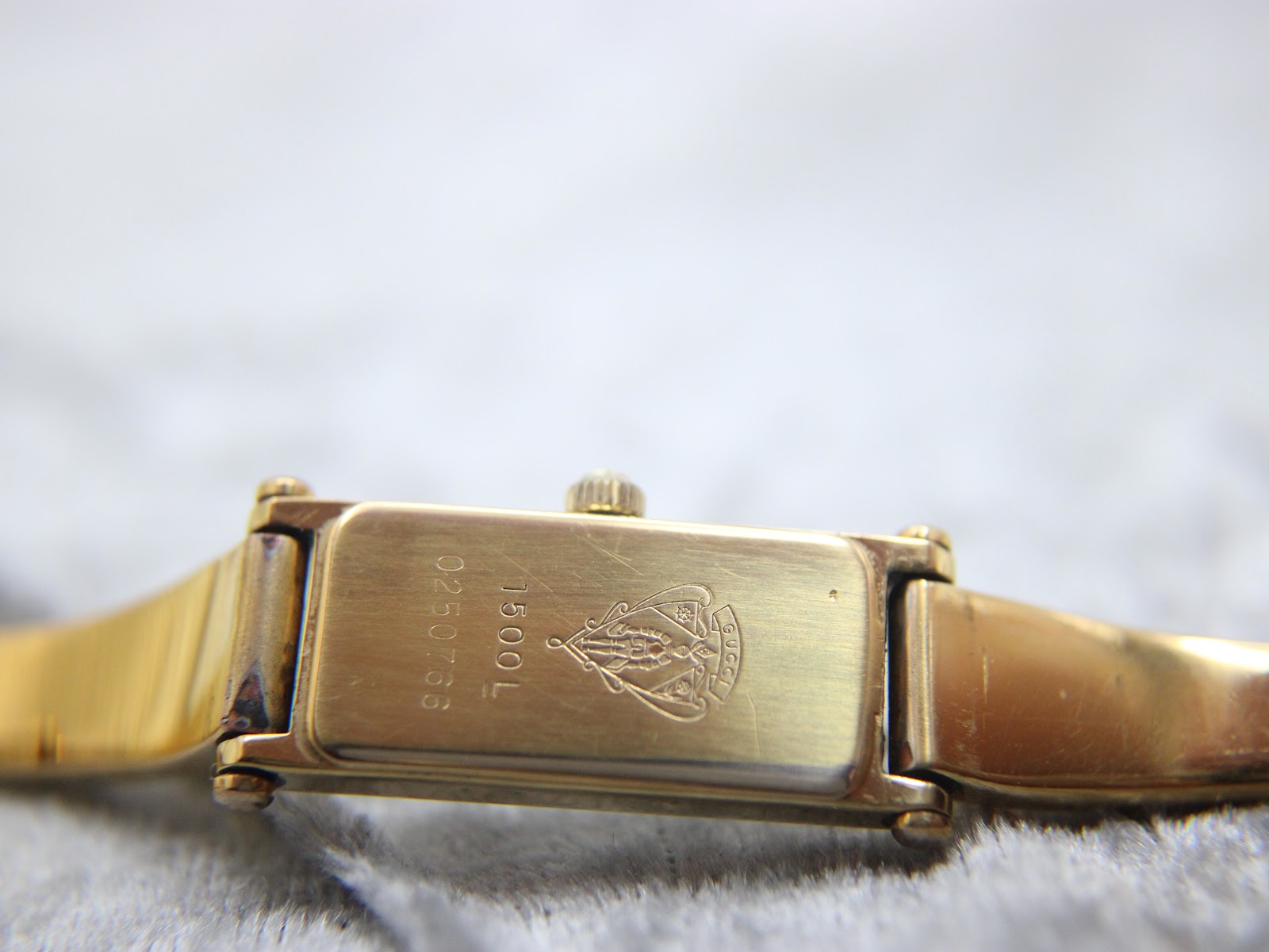 Close-up of the watch case back, showing 'GUCCI' logo, '1500L', and serial number '0250756'.