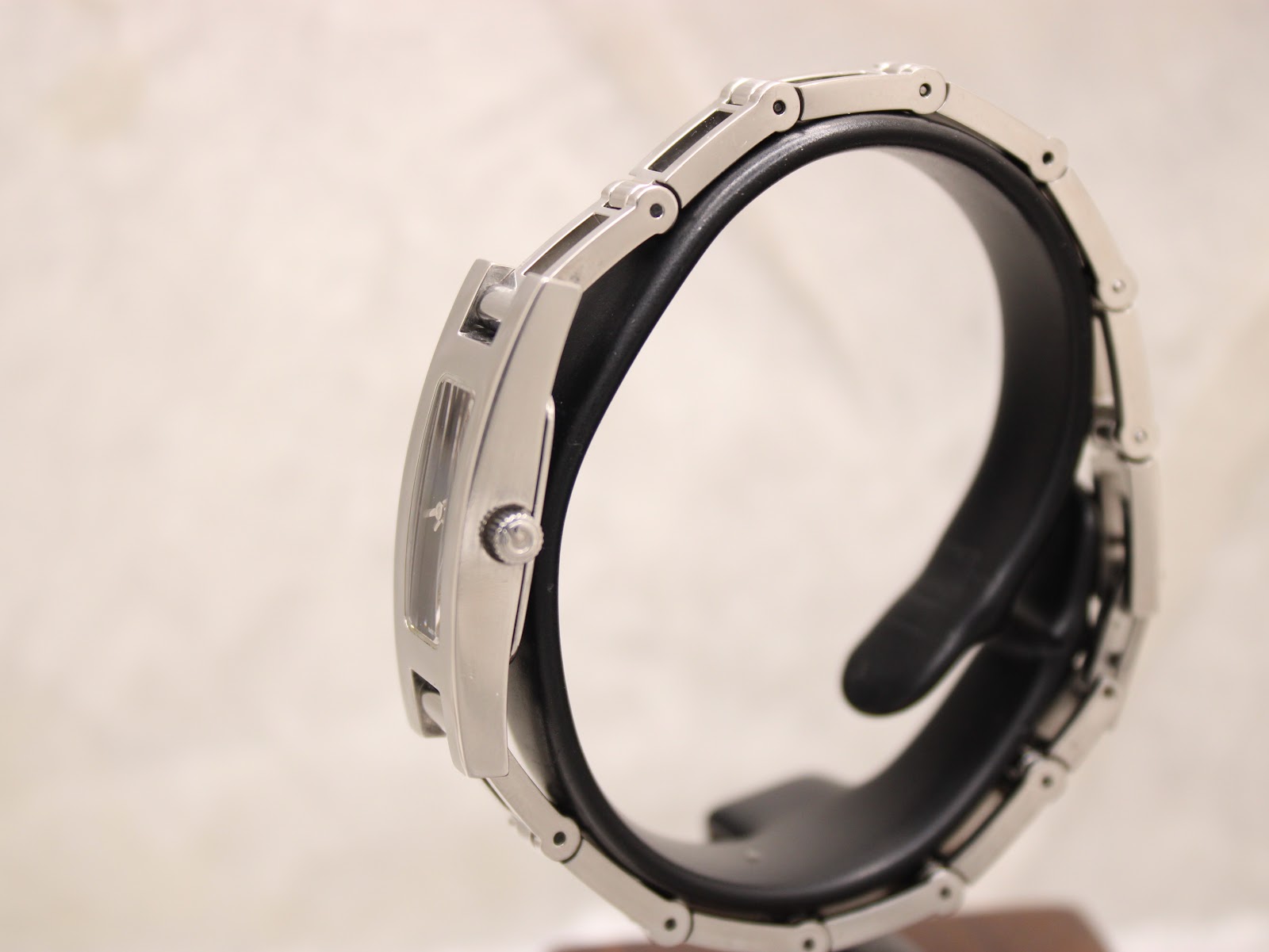 Side view of the Gucci 3900L watch on a stand, highlighting the slim profile and integrated bracelet design.