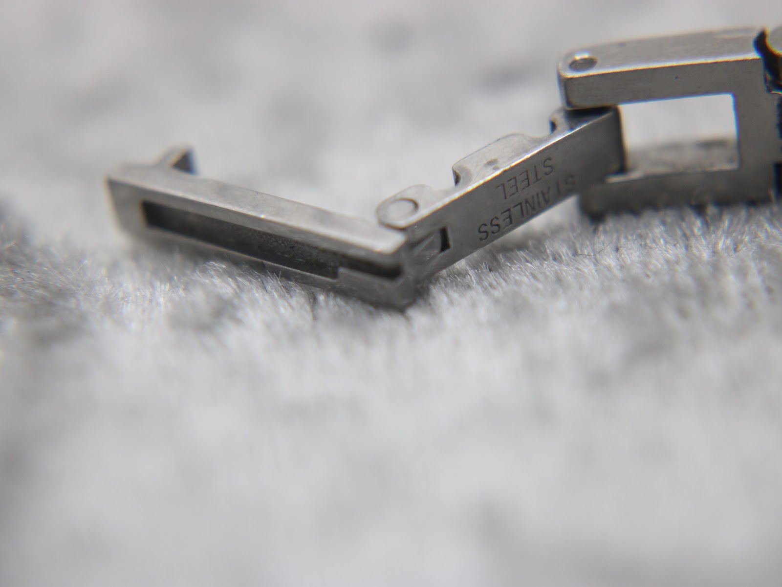 Close-up of the hidden butterfly clasp, showing "STAINLESS STEEL" engraving.