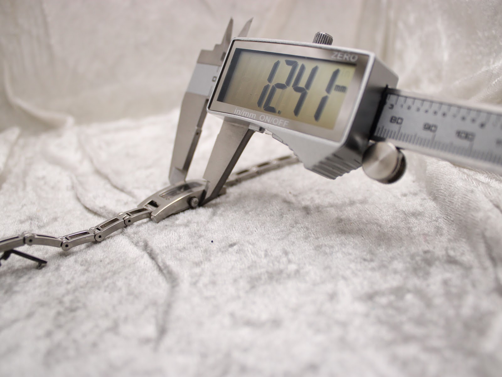 Close-up of a digital caliper measuring the width of the watch case at 12.41mm.