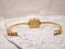 Back view of the Gucci 1900L watch with the gold-plated bangle bracelet laid flat, showing the case back and clasp mechanism.