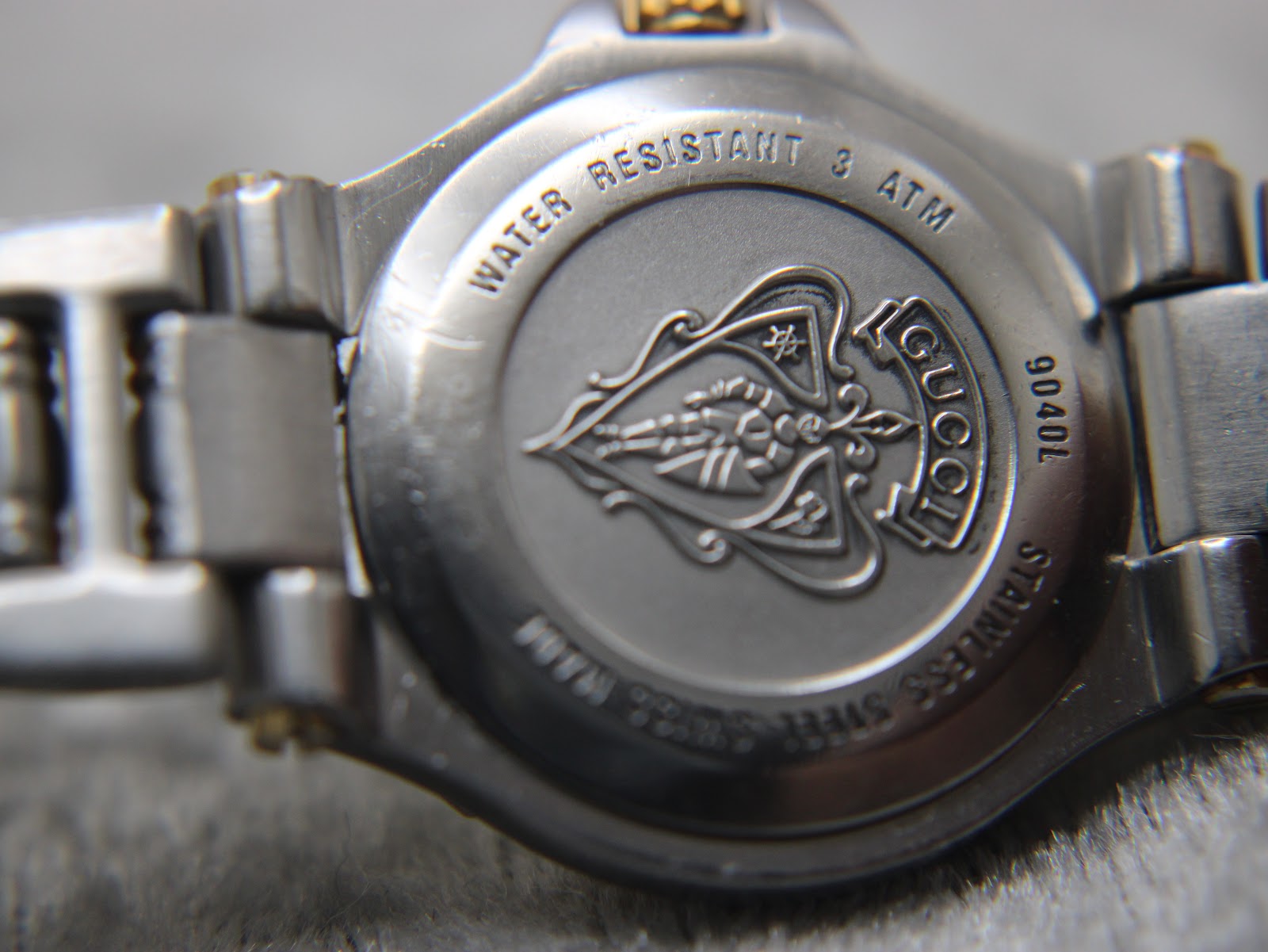 Close-up of the Gucci 9040L watch case back with 'WATER RESISTANT 3 ATM' and the intricate Gucci logo engraving.