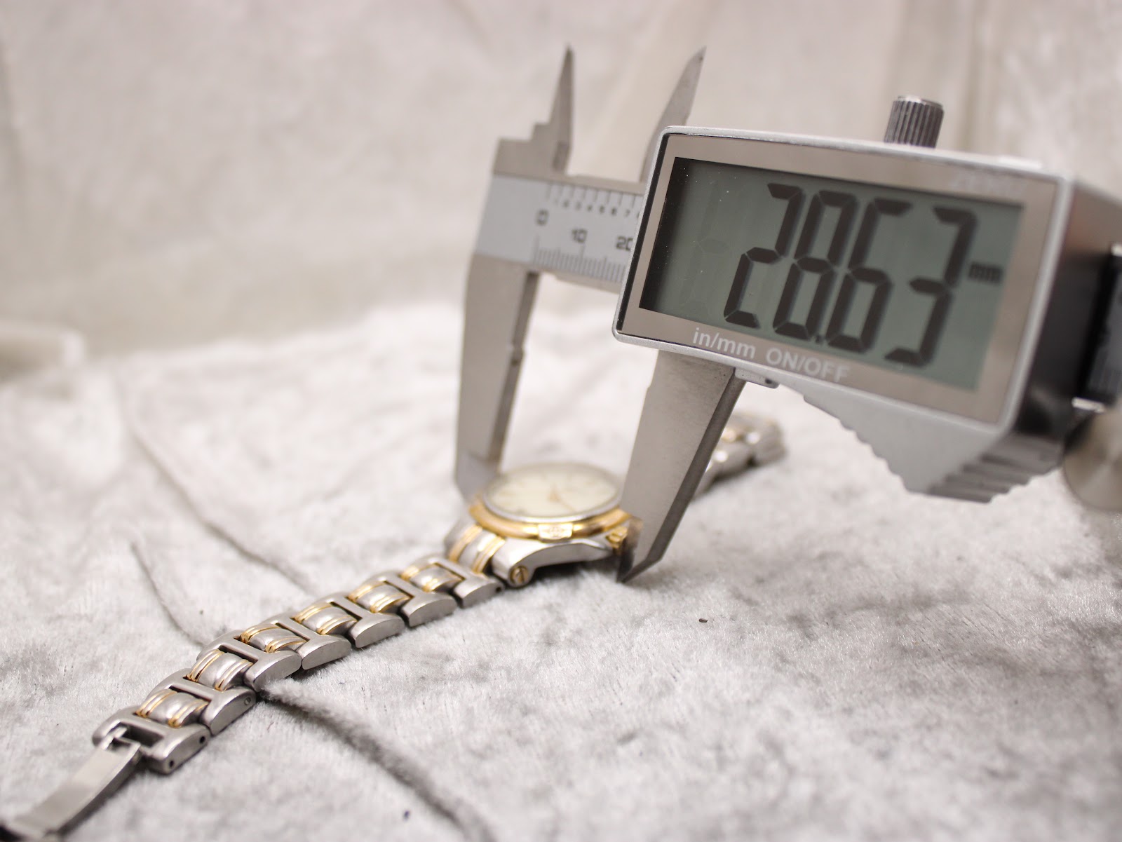 A digital caliper measuring the Gucci 9040L watch case diameter, displaying a precise reading of 28.63mm.