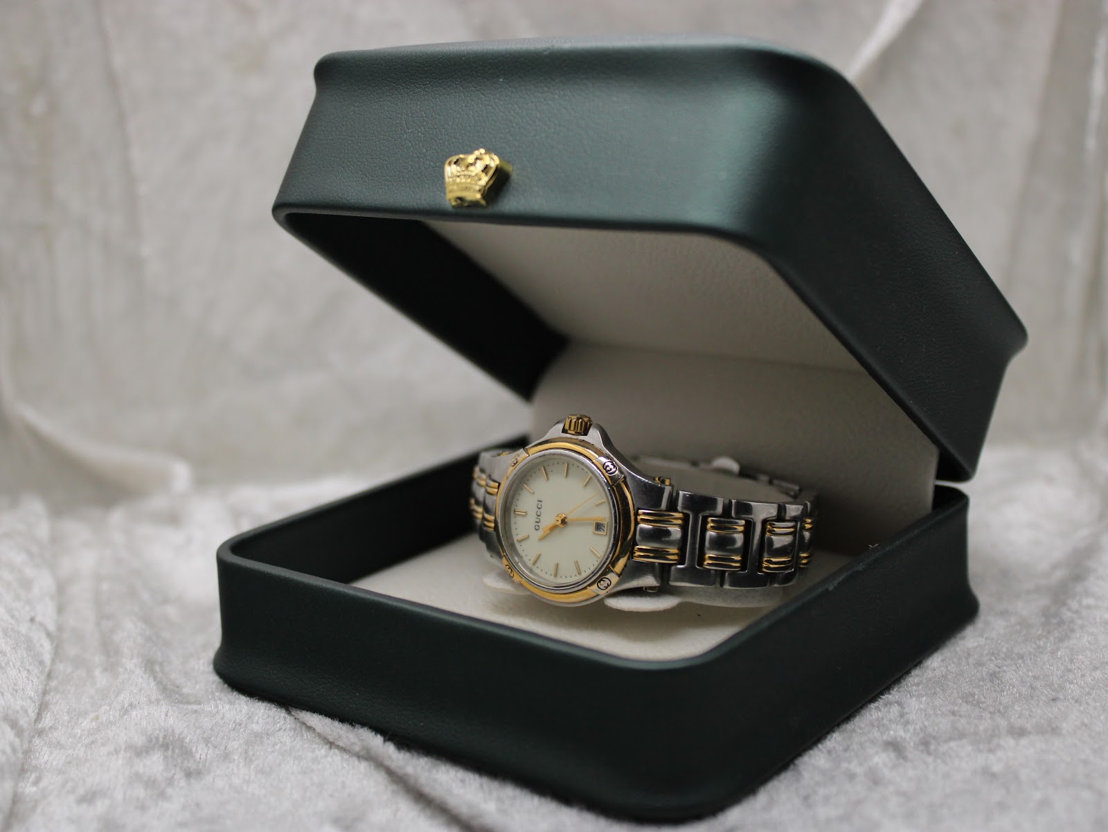 The Gucci 9040L watch displayed inside a dark green presentation box with a gold crown emblem on the lid.