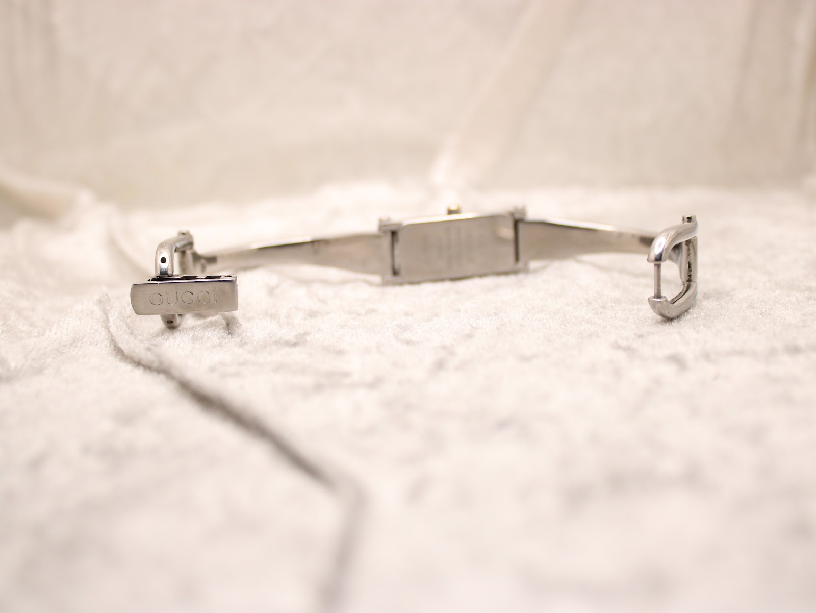 Close-up of the signed Gucci fold-over clasp on the stainless steel bangle bracelet.