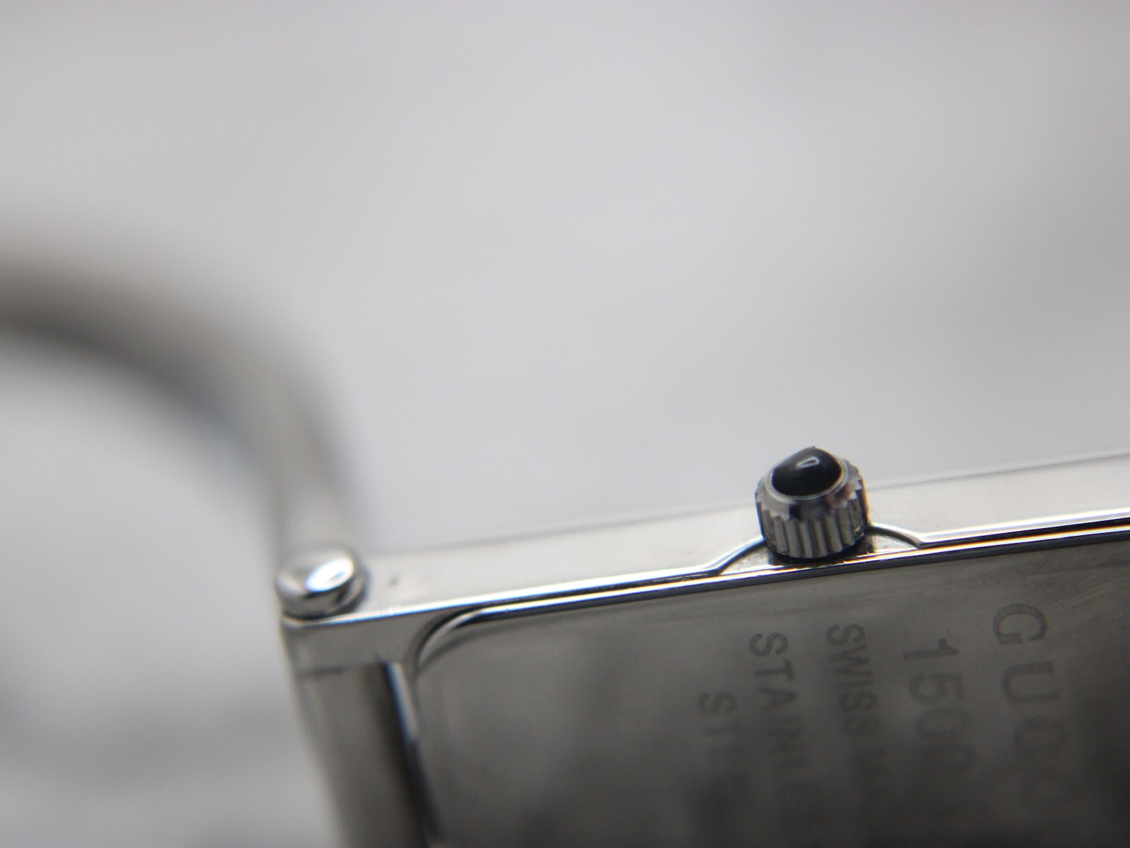 Extreme close-up of the crown with its black cabochon detail and part of the engraved case back.