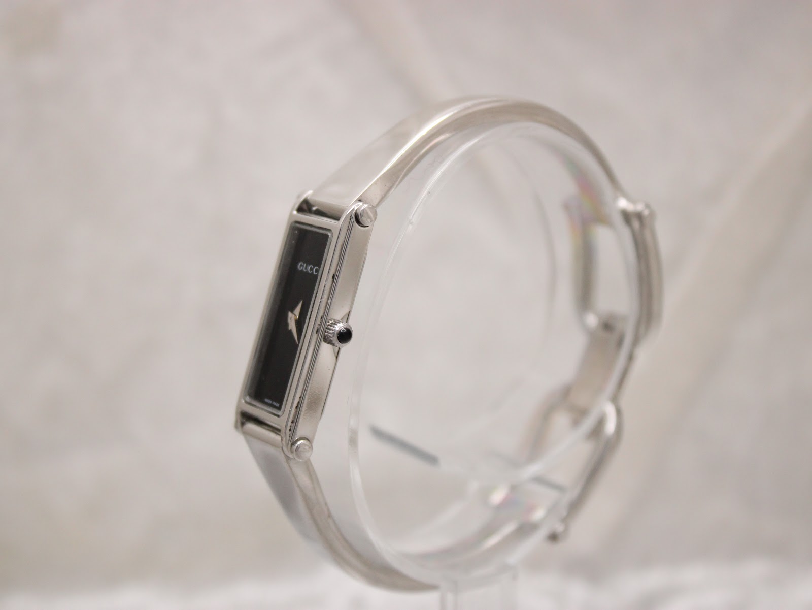 Angled side view of the Gucci 1500L watch, showing the polished stainless steel case and integrated bracelet.
