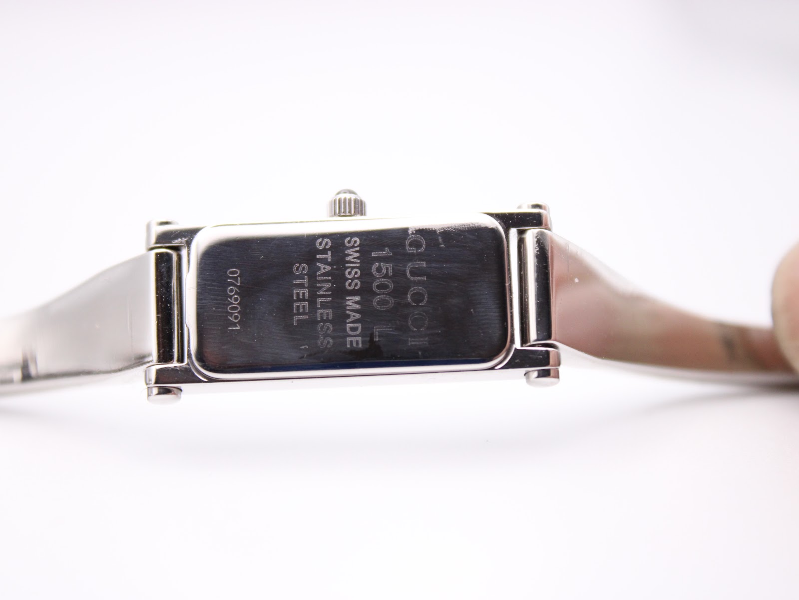 Close-up of the watch case back, engraved with 'GUCCI', '1500L', 'SWISS MADE', 'STAINLESS STEEL', and a serial number '0769091'.