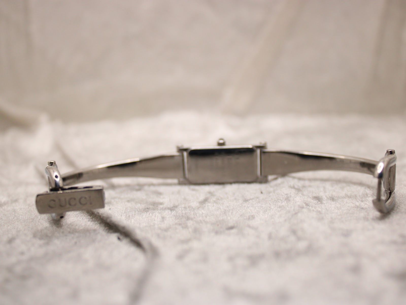 Close-up of the Gucci deployant clasp, showing the 'GUCCI' signature engraved on the inner buckle mechanism.
