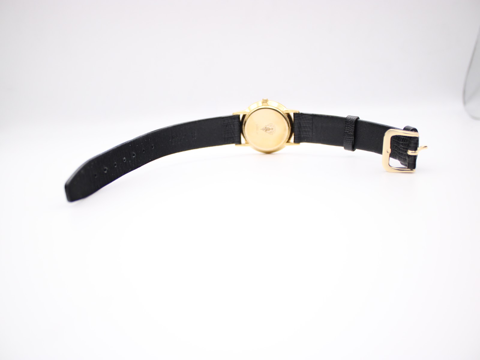 Full view of the Gucci 3000 Jr watch from above, showcasing the black leather strap and gold-plated case.