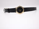 Frontal full view of the Gucci 3000 Jr watch, presenting the black dial, gold tone and textured black leather strap.