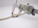 Digital caliper measuring the watch case diameter, displaying an exact measurement of 25.48 mm, with the bi-metal bracelet visible.
