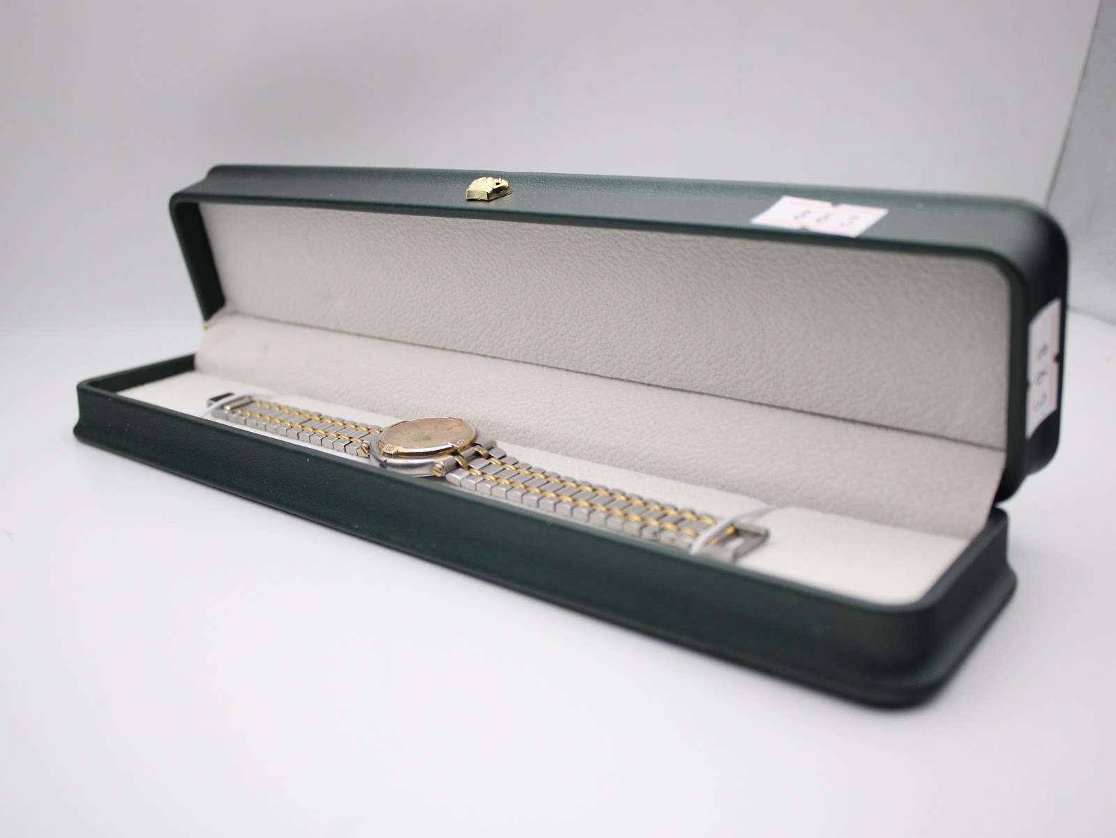 The Gucci 9000 L watch resting neatly inside an open, dark green presentation box with a soft, cream-coloured interior lining.