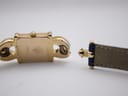 Close-up of the detached strap end and the gold plated case back, highlighting the strap attachment.