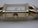 Close-up of the right side of the gold plated watch case showing the crown with a Gucci logo and visible plating wear.