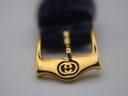 Close-up of the gold-tone buckle with an engraved Gucci interlocking G logo.