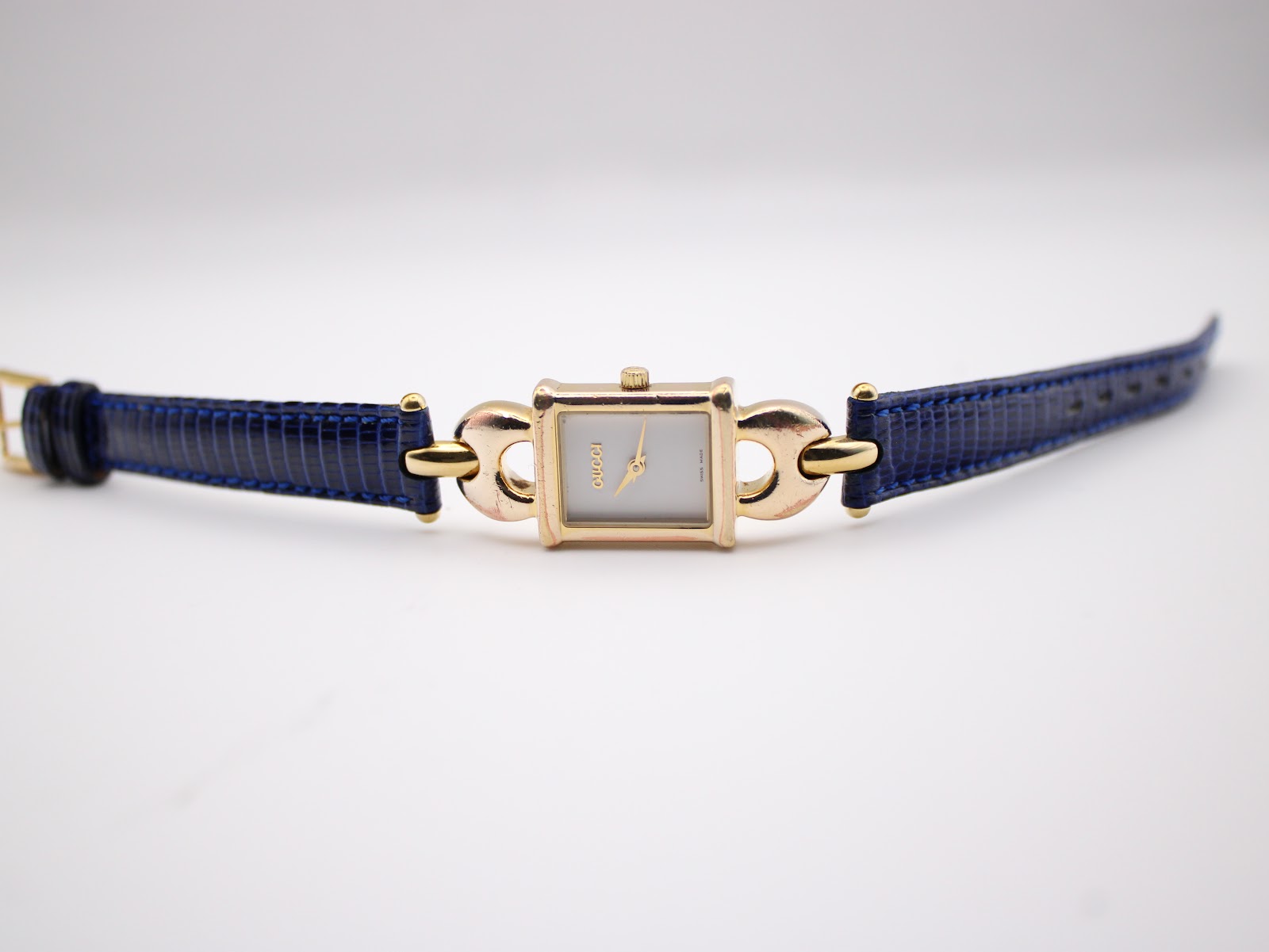 Full view of the Gucci 1800 L watch with the blue leather strap laid flat on a white surface.