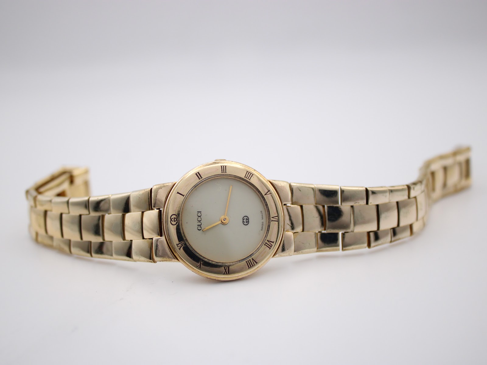Full length view of the Gucci 3300L watch with its gold-plated bracelet extended, against a light background.