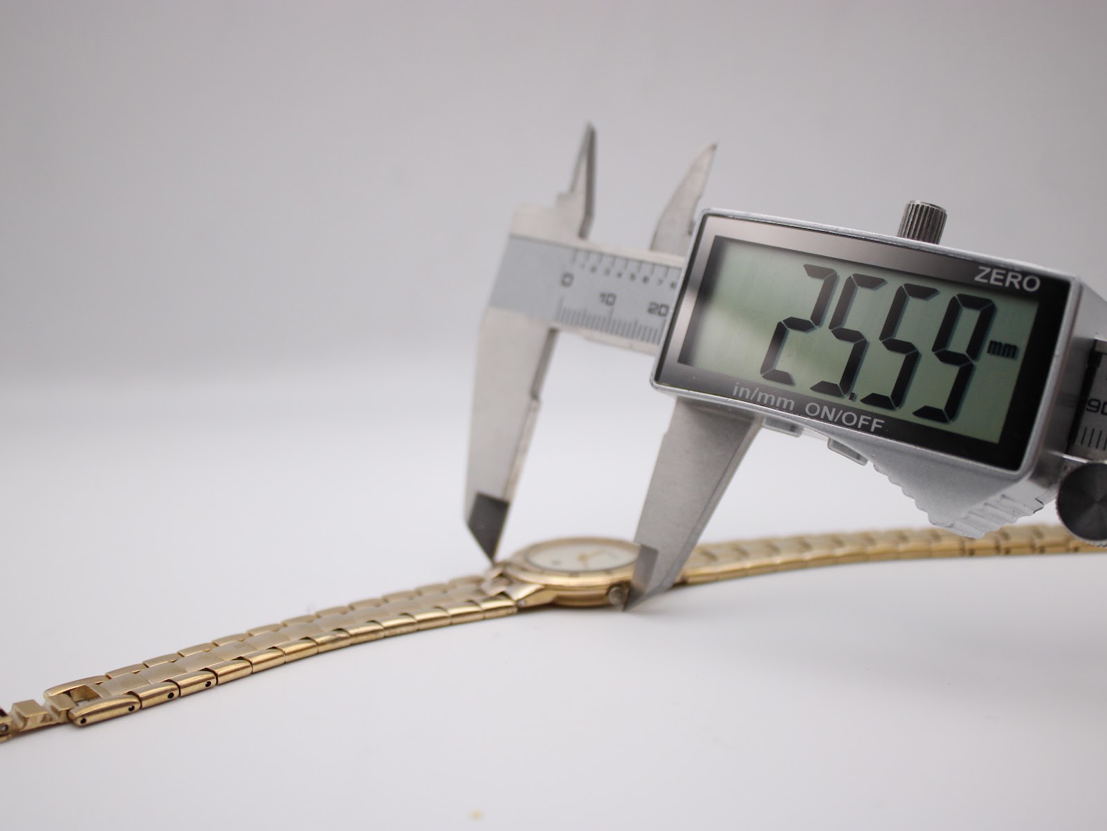 Digital caliper measuring the Gucci 3300L watch case diameter, displaying an exact measurement of 25.59mm.